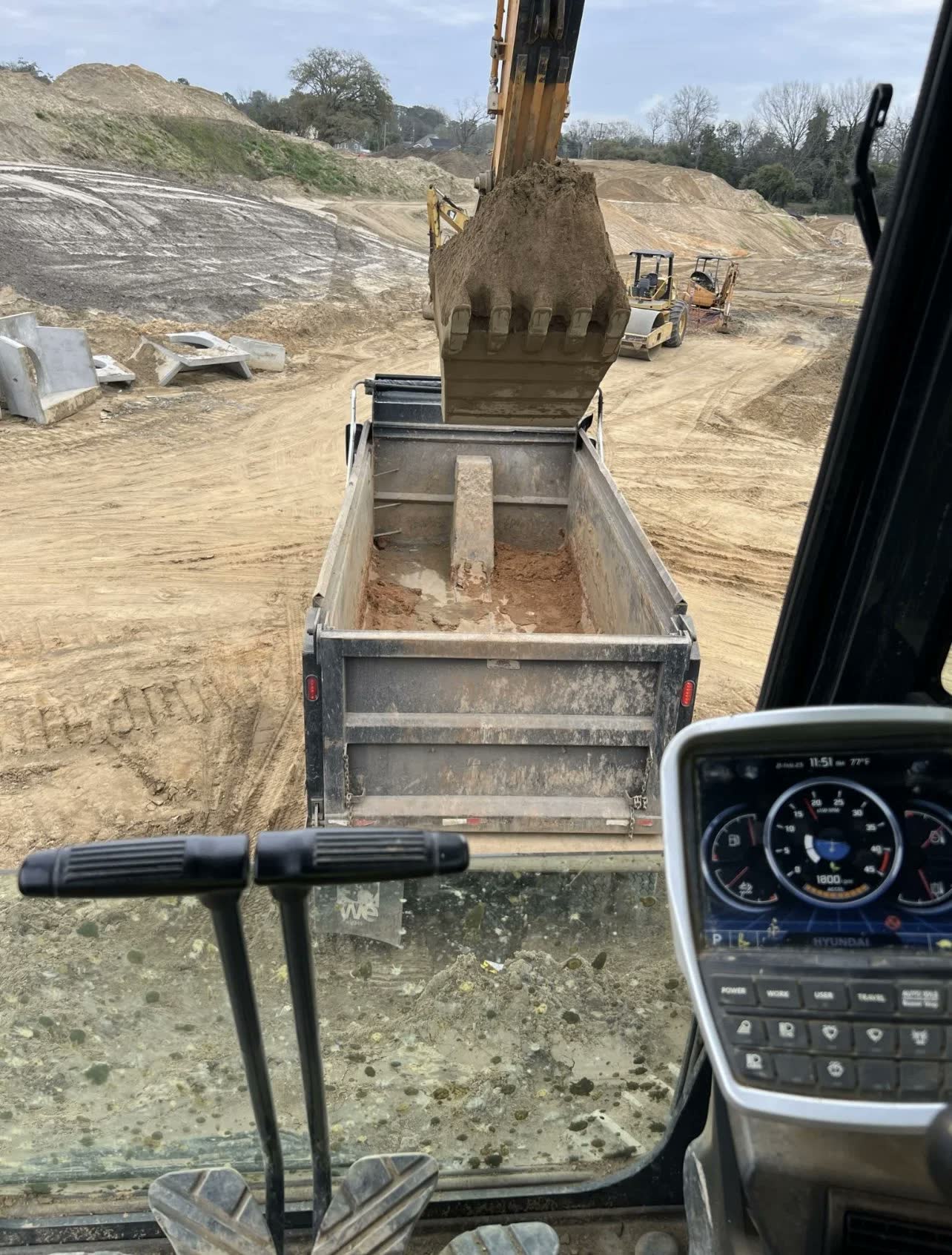 Dozer trimming a grass slope while a truck loads out material.