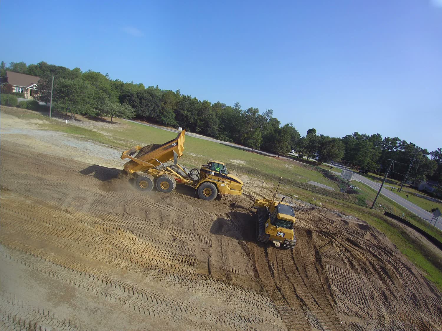 Open utility trench with a worker guiding an excavator bucket.
