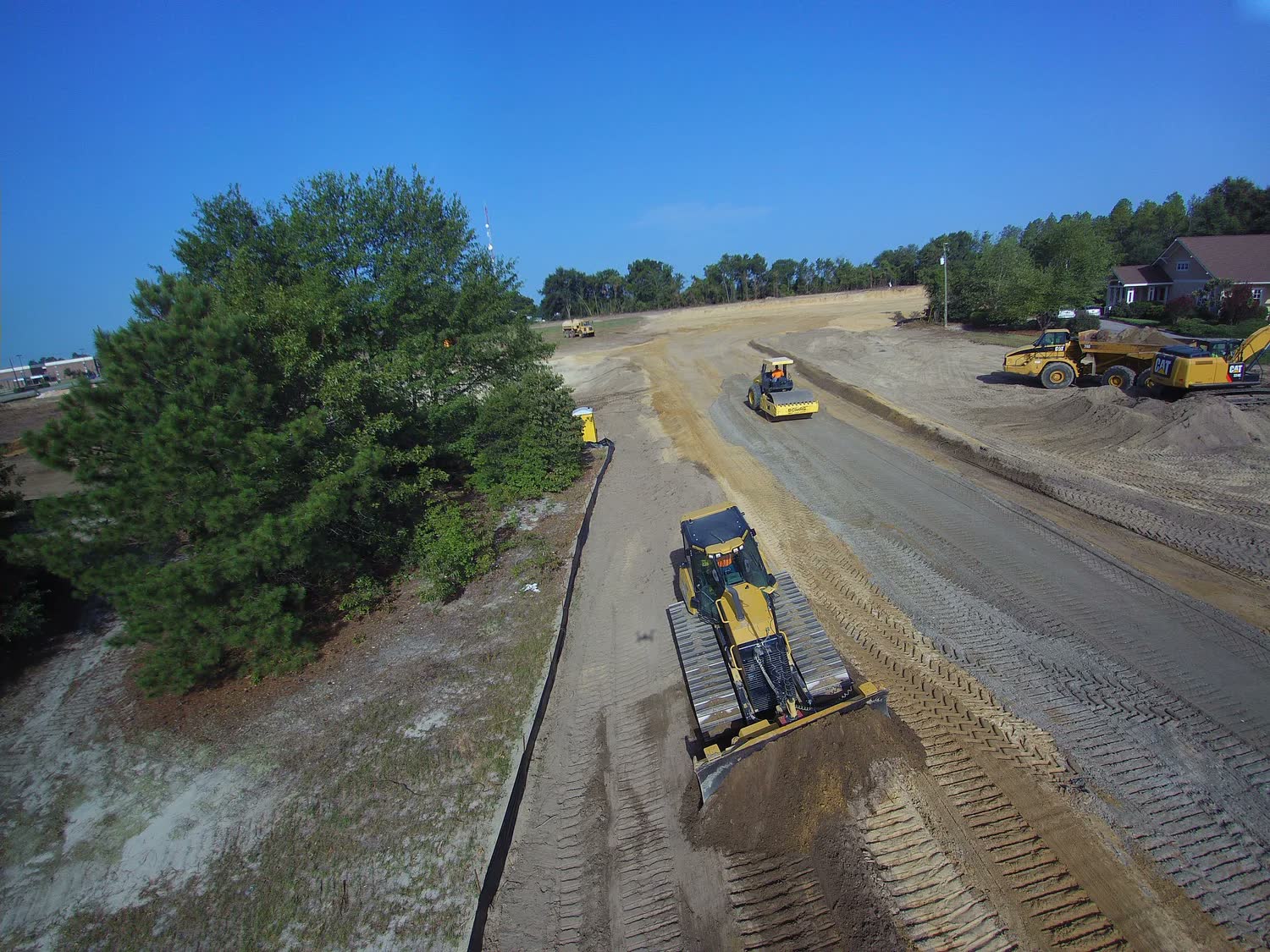 Asphalt paver placing a lane, with a steel-drum roller behind it.